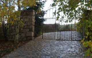 L'allée de pavés et le portail en fer forgé ancien