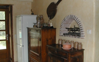 La cuisine de ma maison de campagne - Niche décorative avec sa vieille balance, placard de rangement et combiné frigidaire congélateur au fond.