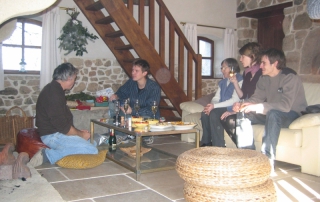 Soirée entre amis pour arroser un anniversaire devant la cheminée en pierre dans le salon bibliothèque.