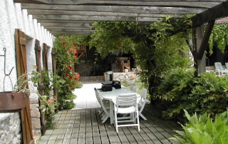 Une terrasse en bois avec une glycine vous abritera du soleil pour prendre vos repas ou petits déjeuners