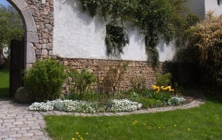 Massif de fleurs et rosiers dans le jardin à droite du porche