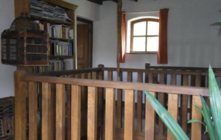 Contre plongée de la bibliothèque en haut avec son plafond en bois à la française. Hauteur de plafond 5 mètres. Escalier en chêne pour accéder à l'étage supérieur. 