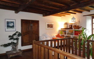 A l'étage, la pièce bibliothèque et sa rembarde de la corbeille en chêne avec vue sur le salon du bas et la cheminée en pierre d'époque.