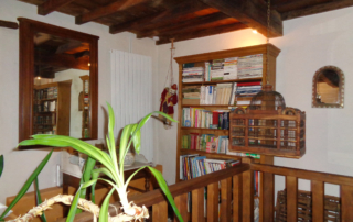 Vue du salon du bas avec canapé en cuir blanc donnant sur une cheminée en pierres d'époque.