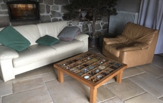 Le salon de ma maison de campagne - Canapé 3 places et 2 fauteuils en cuir et vue sur le mur en pierres avec l'insert