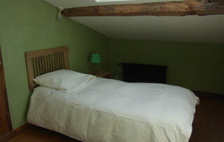 Chambre sous les toits communiquant avec la mezzanine, avec 2 lits en 90 pour 1 personne, poutre en chêne au plafond.