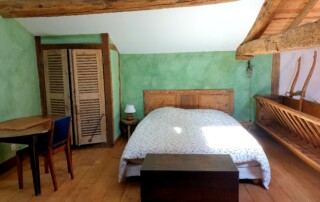 Mezzanine avec grand lit en 160, sur la droite meuble mangeoire et sur la gauche armoire murale avec ses volets anciens en bois en guise de porte.
