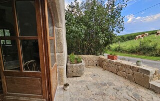 Terrasse extérieure du duplex donnant sur la route avec son auge en pierre.