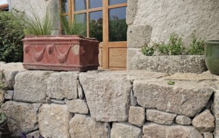 Façade extérieure du duplex avec sa voute en pierre et terrasse extérieure avec son mur en pierre côté route.